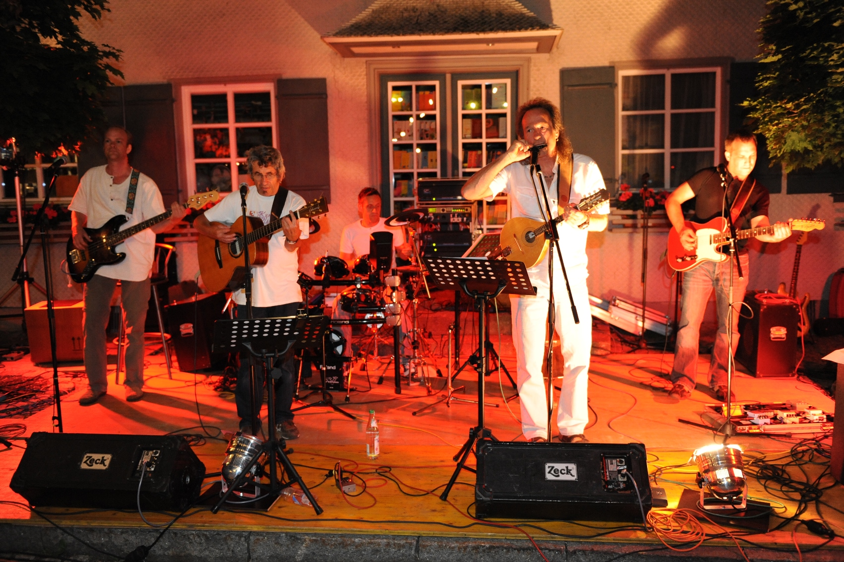  Band spielt auf einer Bühne und wird mit rotem Licht beleuchtet - das Bild wird mit Klick vergrößert 