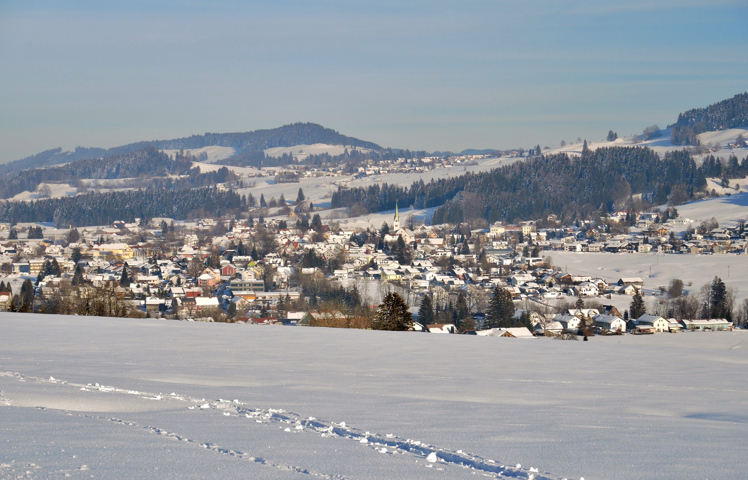  Im Vordergrund der Winterlandschaft ist ein schneebedecktes Feld und im Hintergrund der Ort Weiler - das Bild wird mit Klick vergrößert 