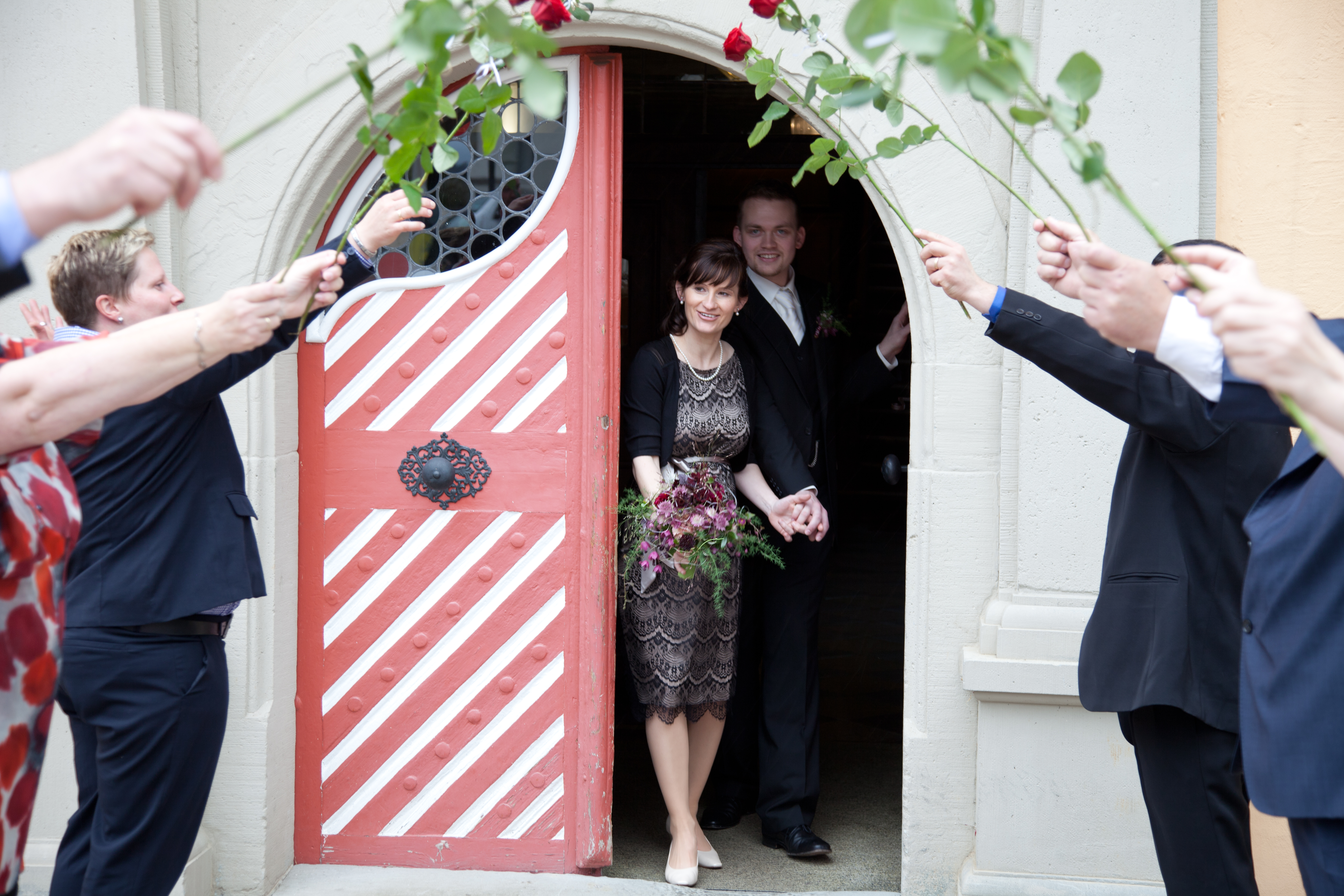 Das frisch getraute Brautpaar kommt aus der Eingangstüre des Rathauses in Weiler heraus. Die Hochzeitsgesellschaft steht mit roten Rosen Spalier - das Bild wird mit Klick vergrößert 