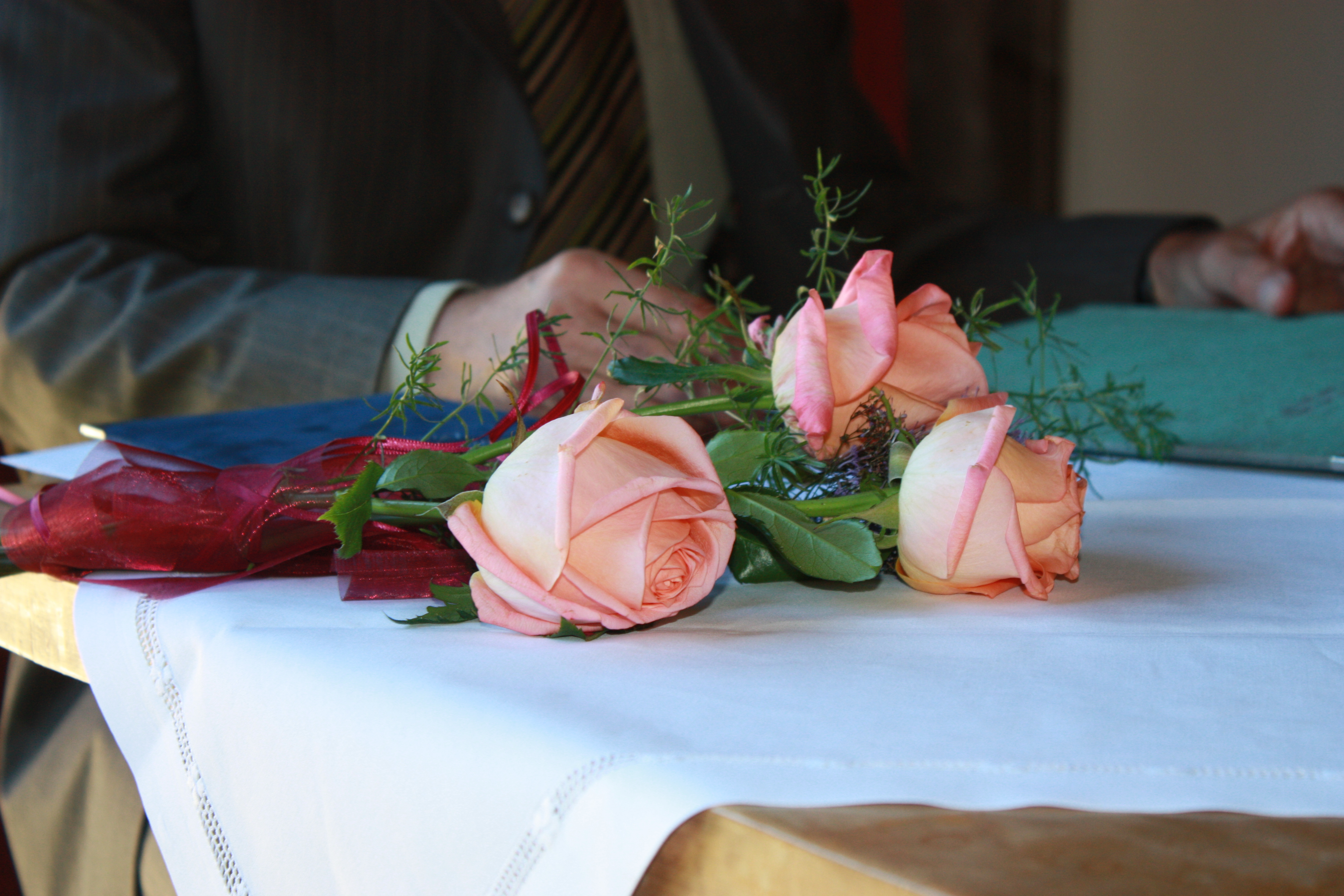  Auf einem Tisch mit weißer Tischdecke liegen rosa Rosen - das Bild wird mit Klick vergrößert 