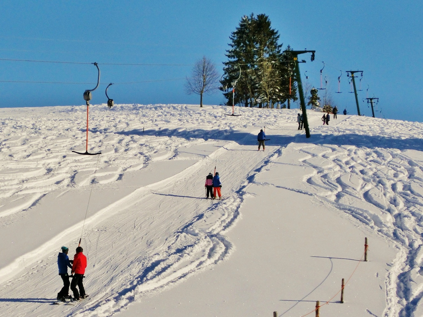  Skifahrer werden bei blauen Himmel am Skilift den schneebedeckten Berg hochgezogen - das Bild wird mit Klick vergrößert 